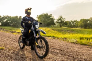 Dynamic shot of the Sur Ron Ultra Bee T & R (Road Legal) electric motorcycle navigating a winding European road, showcasing its integrated LED lighting, mirrors, and dual-sport tires.